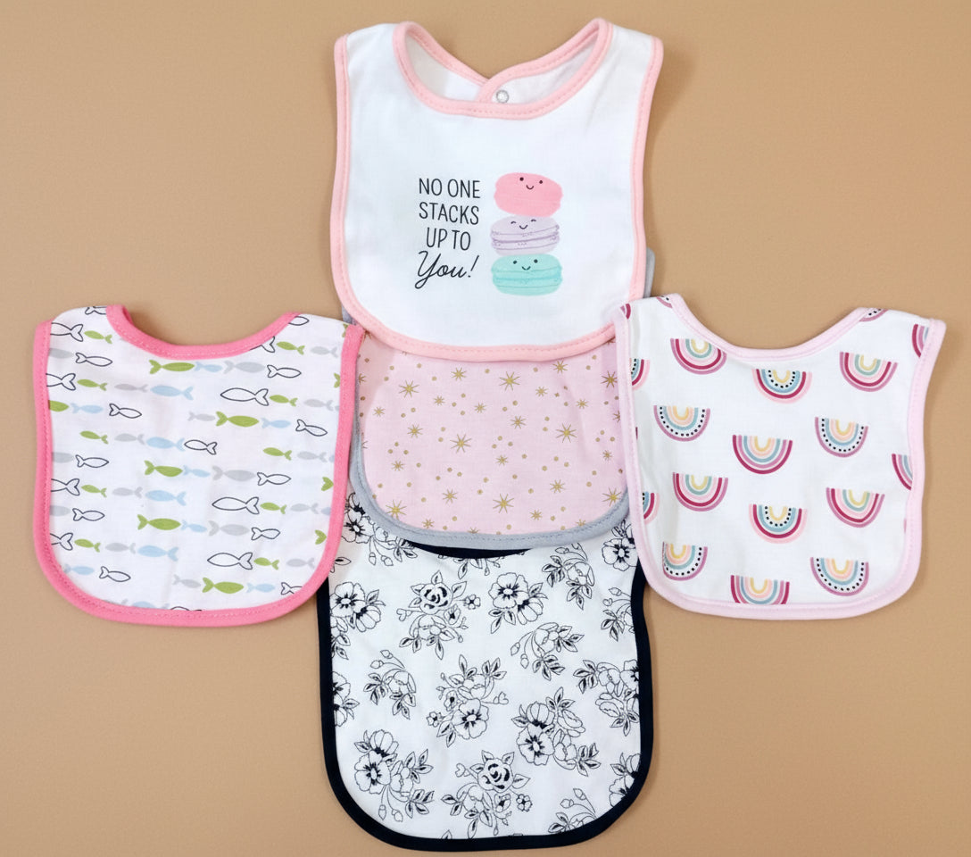 Set of five baby bibs with various patterns on a textured surface