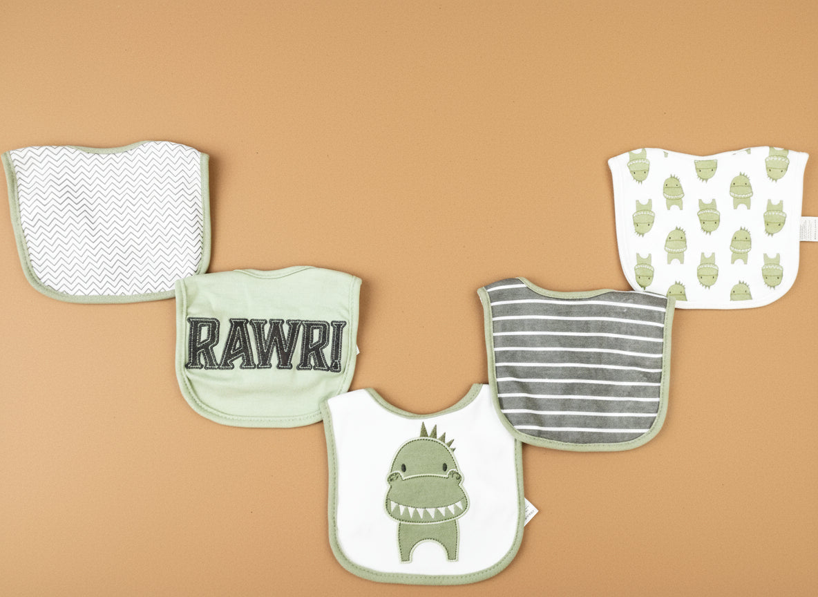 Set of baby bibs and burp cloths with various patterns on a textured surface