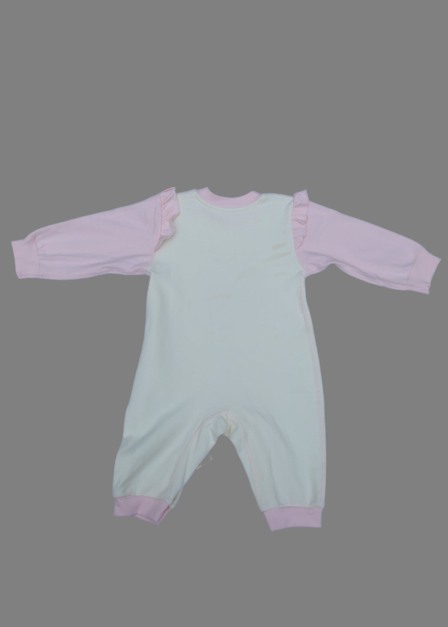 Light green baby romper with pink trim on a light blue surface
