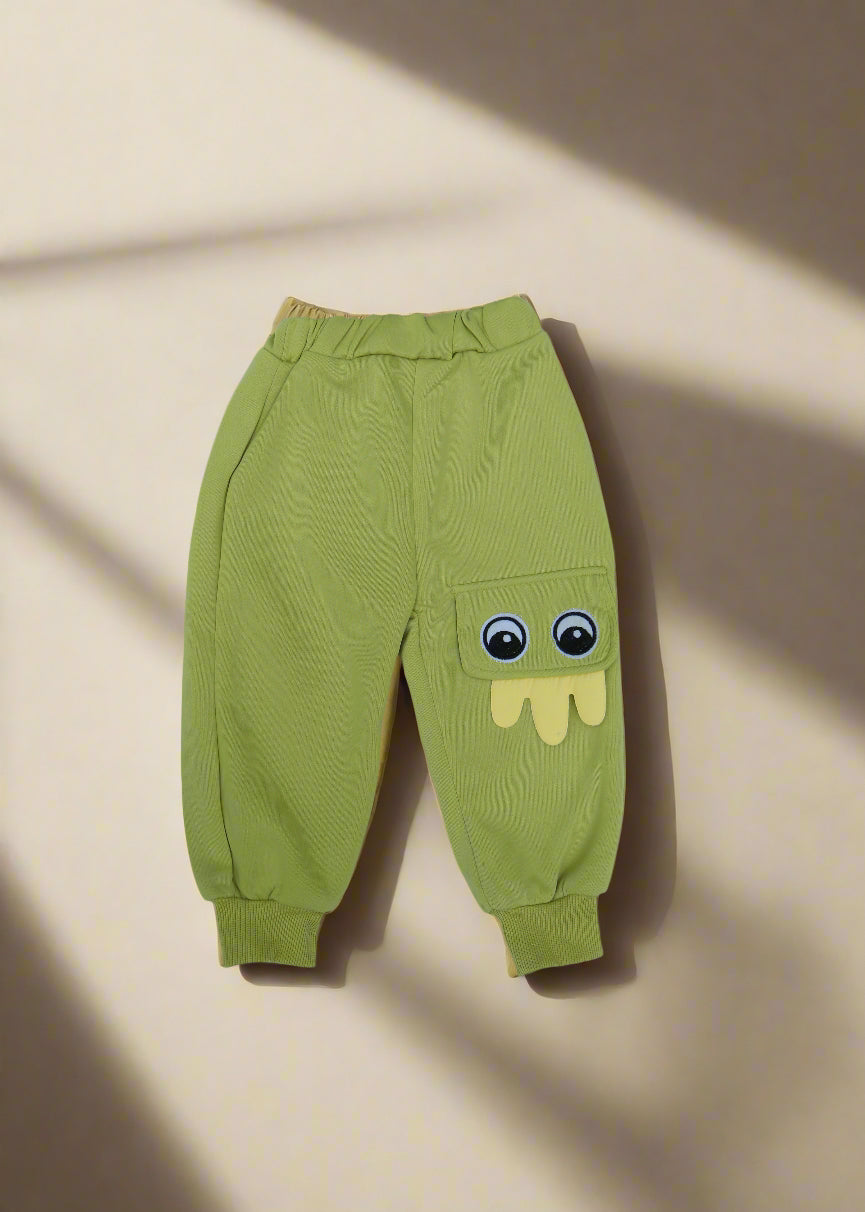 Green baby pants with cartoon face design on a light blue background