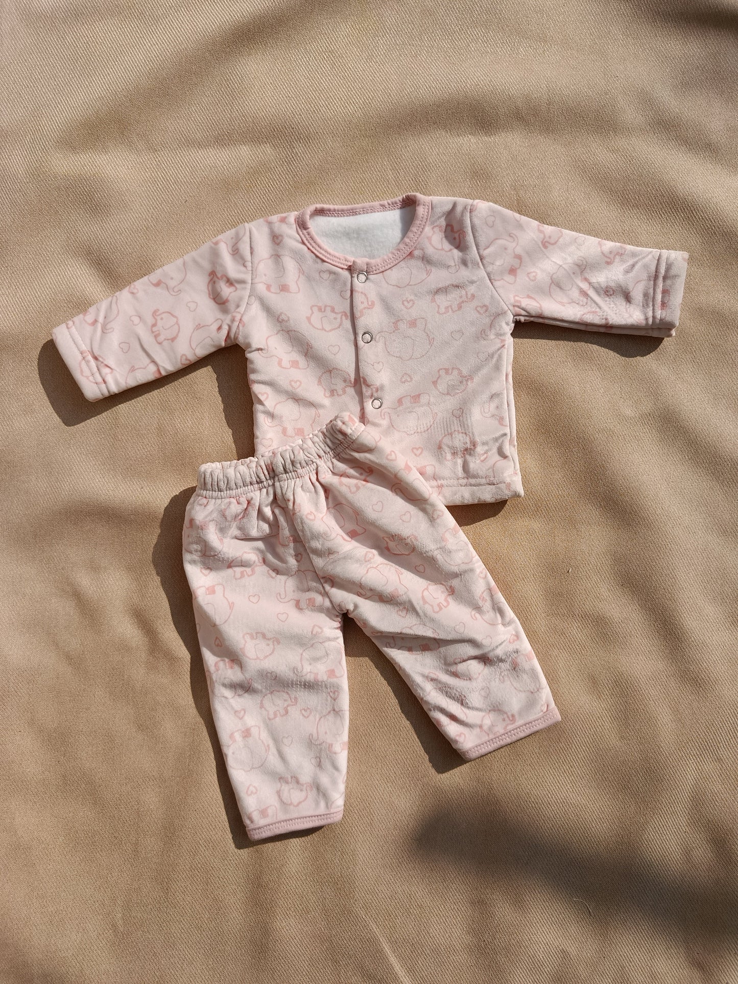 Baby outfit with pink and brown pattern on a beige background