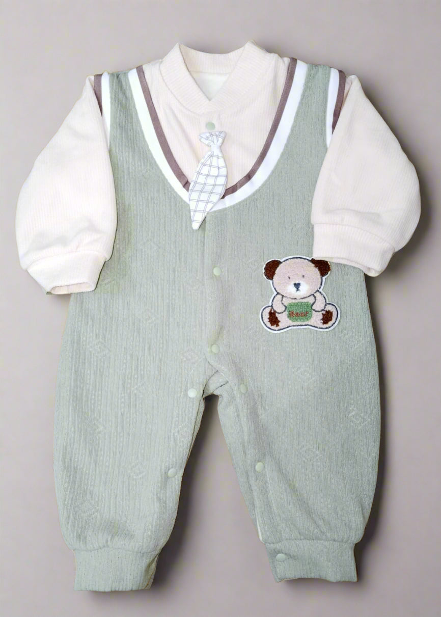Baby outfit with green vest and white shirt on a patterned yellow background