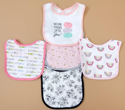 Set of five baby bibs with various patterns on a textured surface