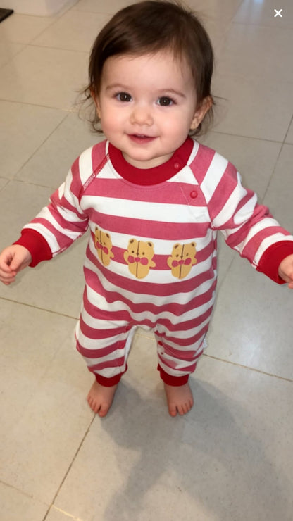 Child wearing a red and white striped onesie with cartoon characters on a tiled floor.