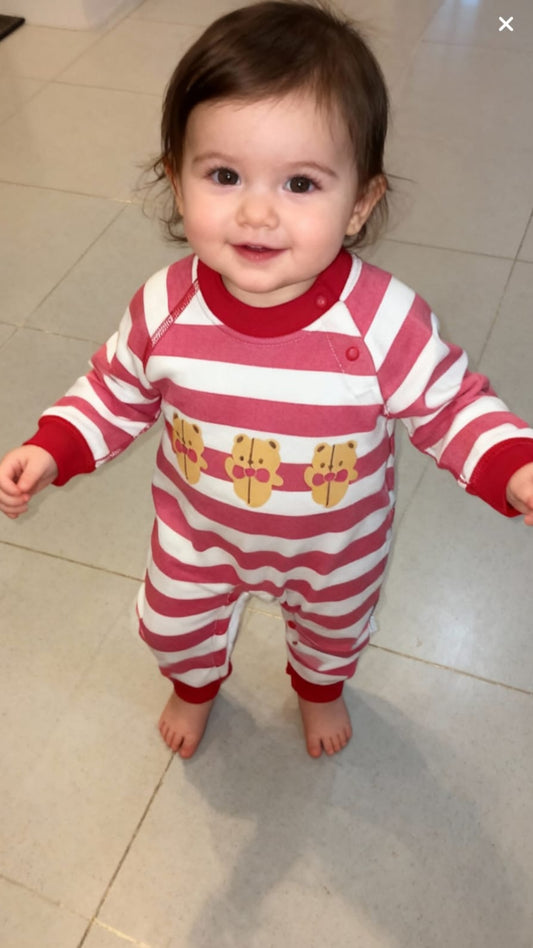 Child wearing a red and white striped onesie with cartoon characters on a tiled floor.
