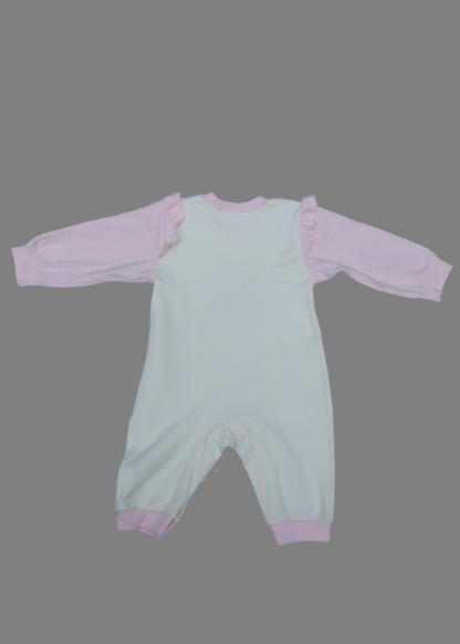 Light green baby romper with pink trim on a light blue surface