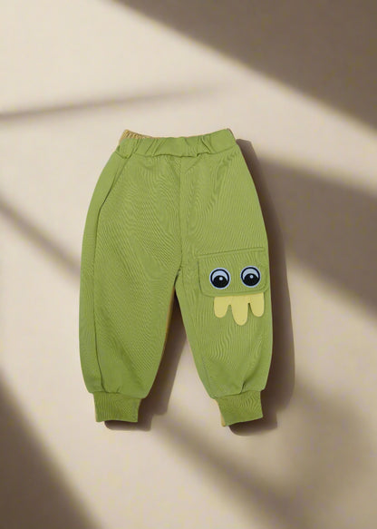 Green baby pants with cartoon face design on a light blue background