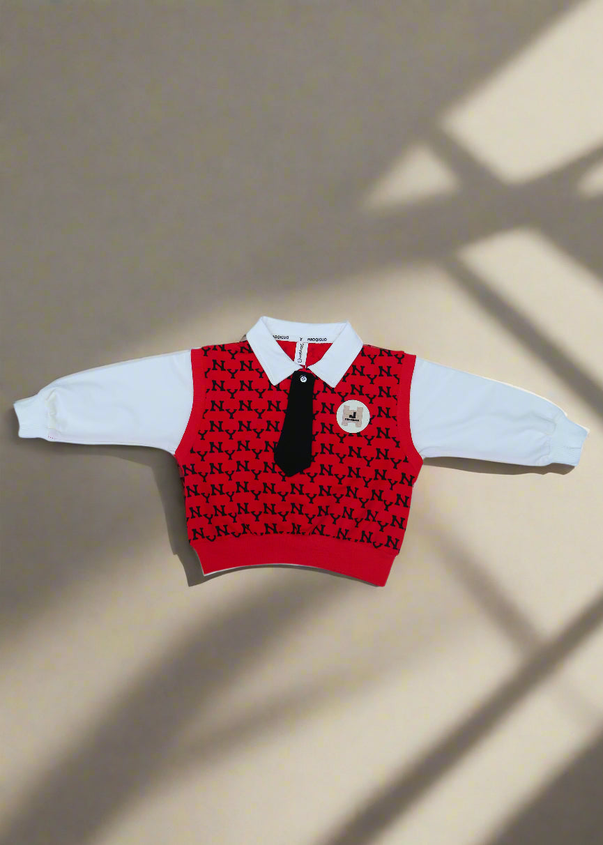 Red and black patterned baby romper with white pants on a white towel.