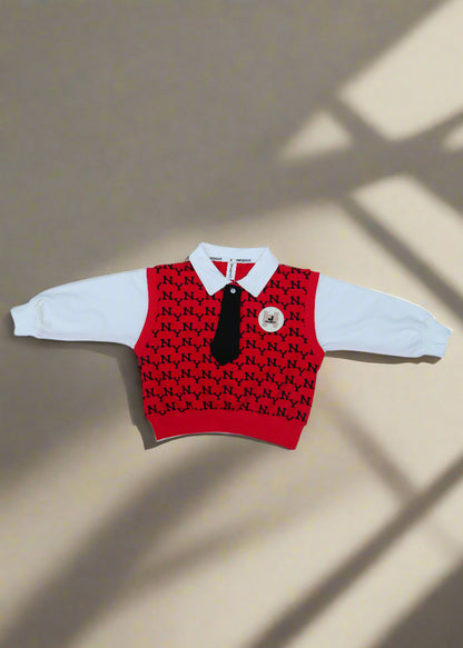 Red and black patterned baby romper with white pants on a white towel.