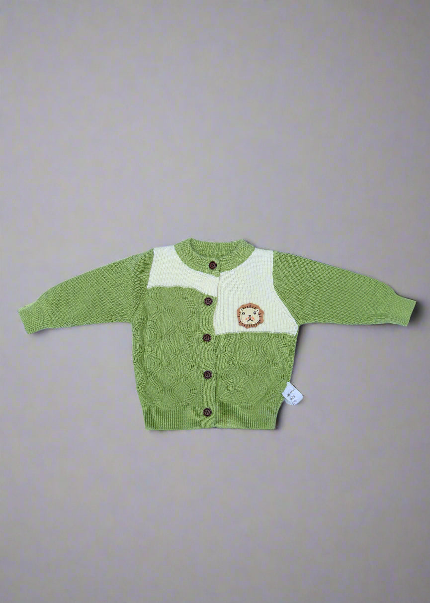 Green baby sweater with white bib on a light blue background