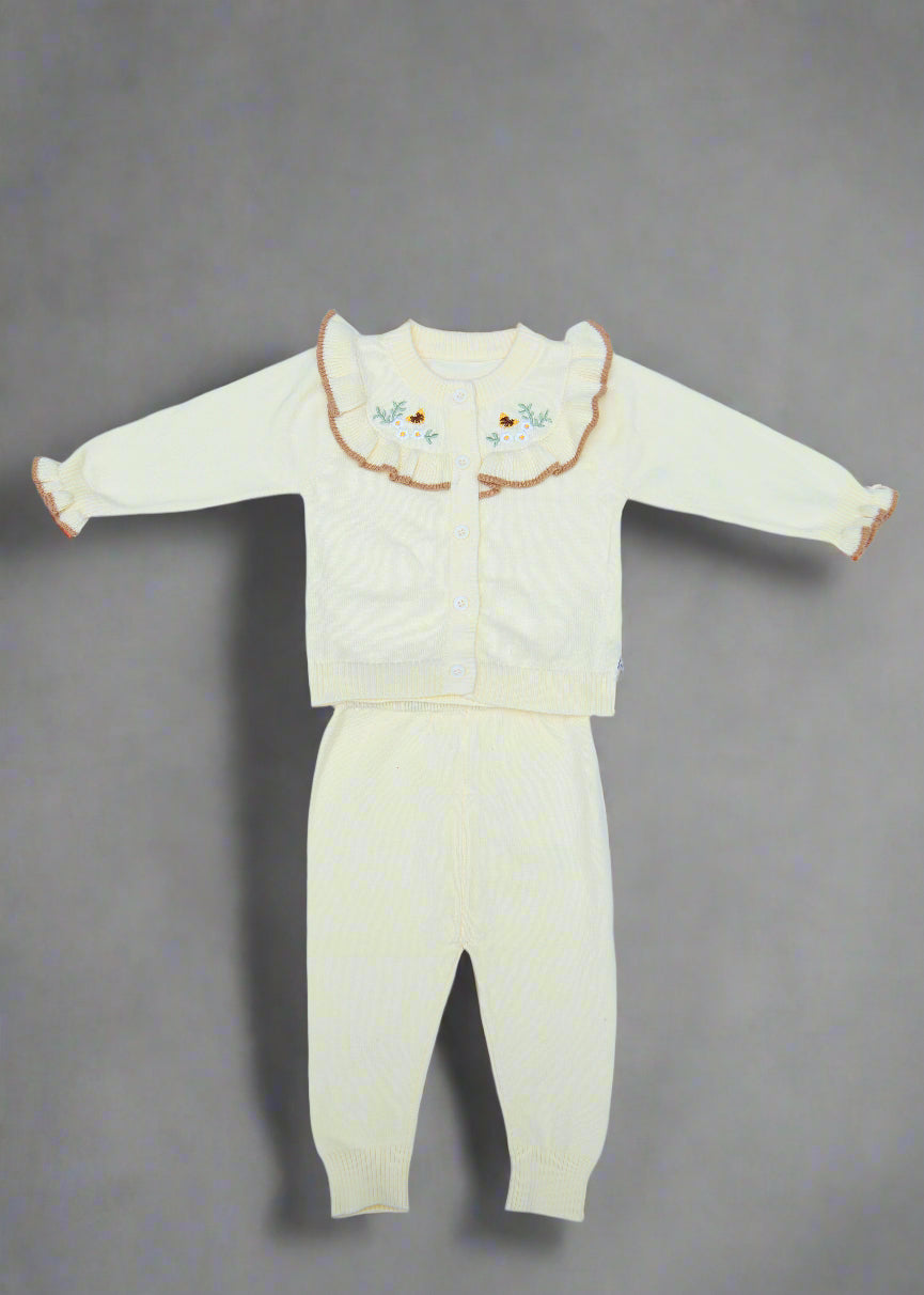 White baby outfit with floral details on a light blue background