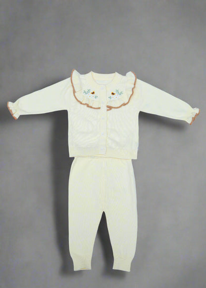 White baby outfit with floral details on a light blue background