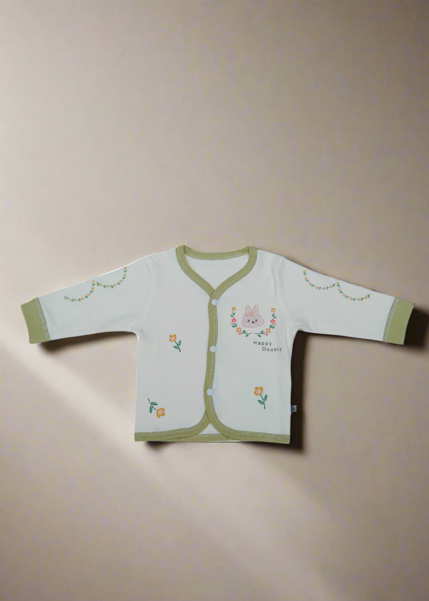 Baby outfit with green trim on a light blue surface