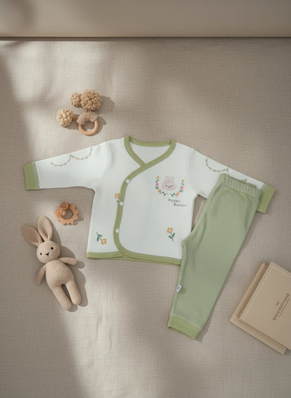 Set of green baby pants and bib on a light blue surface