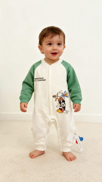 Baby wearing a green and white onesie with cartoon character design on a white background