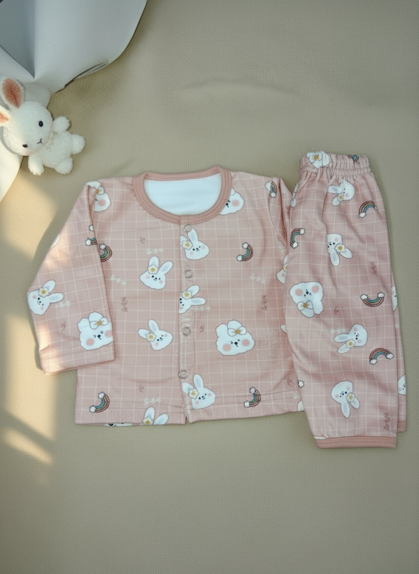 Children's pink pajama set with cartoon designs on a beige surface