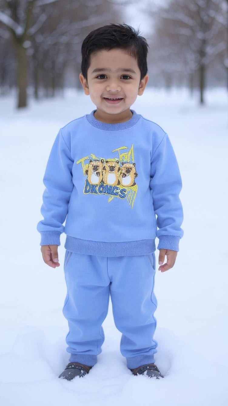 Child wearing a blue sweater and pants set with cartoon characters in a snowy landscape