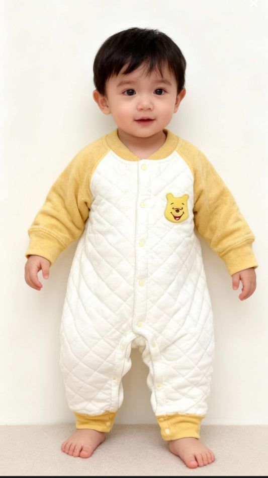 Baby wearing a yellow and white outfit with a cartoon character on a white background