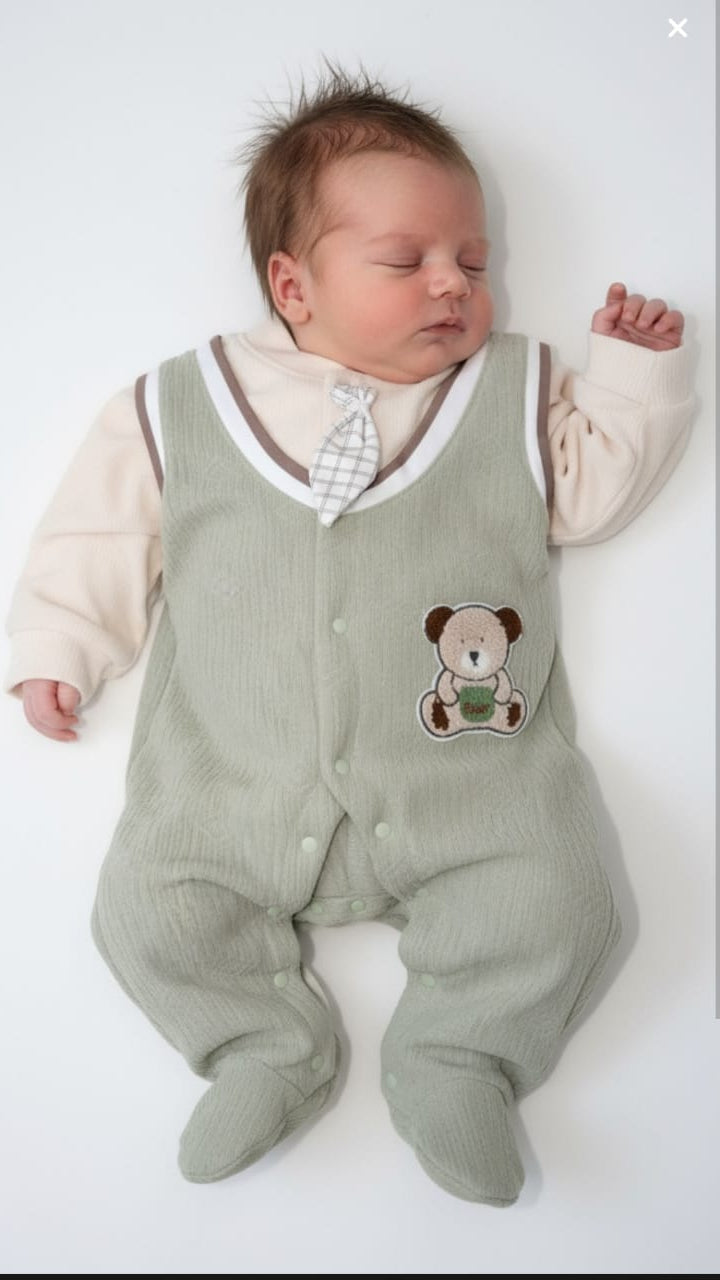 Newborn baby wearing a green romper with a teddy bear design on a white background