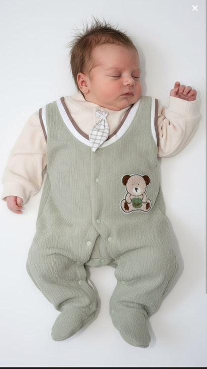 Newborn baby wearing a green romper with a teddy bear design on a white background