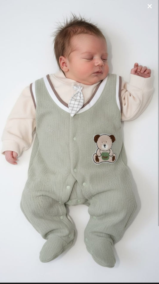 Newborn baby wearing a green romper with a teddy bear design on a white background