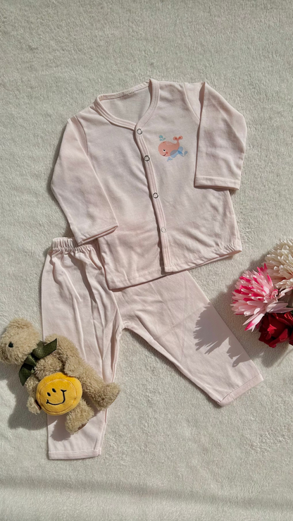 Pink children's outfit with long-sleeve top and pants, accompanied by a teddy bear and flowers on a light background.