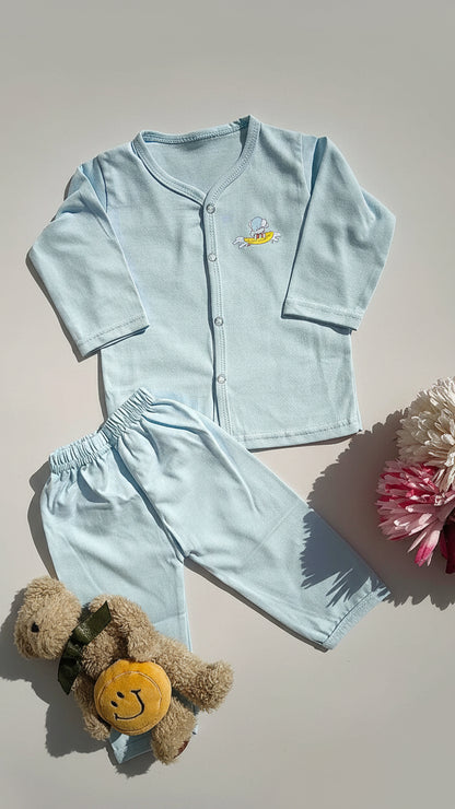 Light blue children's pajama set with a teddy bear on a beige surface