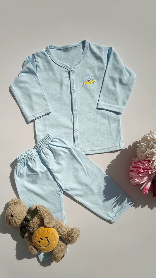 Light blue children's pajama set with a teddy bear on a beige surface