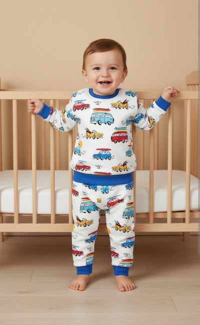 Child wearing pajamas with vehicle prints standing in front of a crib.