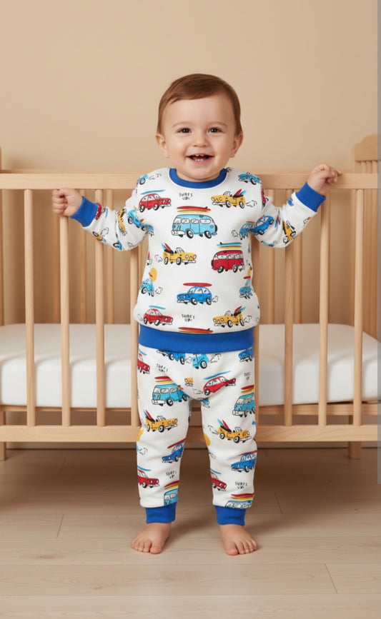 Child wearing pajamas with vehicle prints standing in front of a crib.