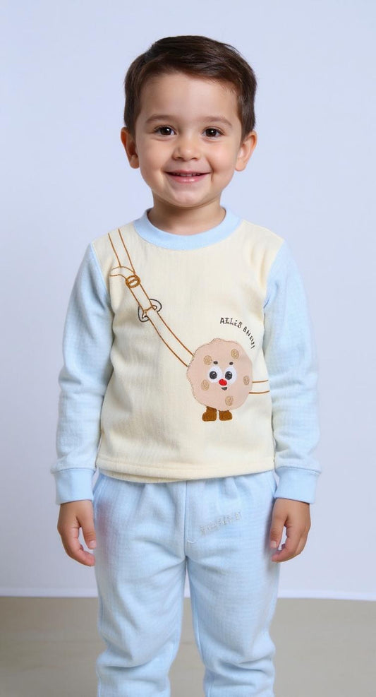 Child wearing a light blue shirt with a cartoon design and beige pants on a white background