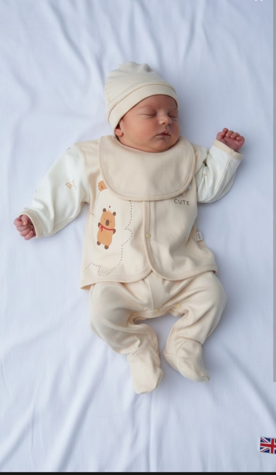 Newborn baby in a cream outfit with bear design on a white background