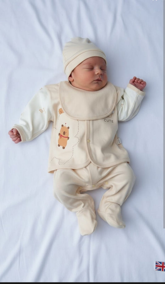 Newborn baby in a cream outfit with bear design on a white background