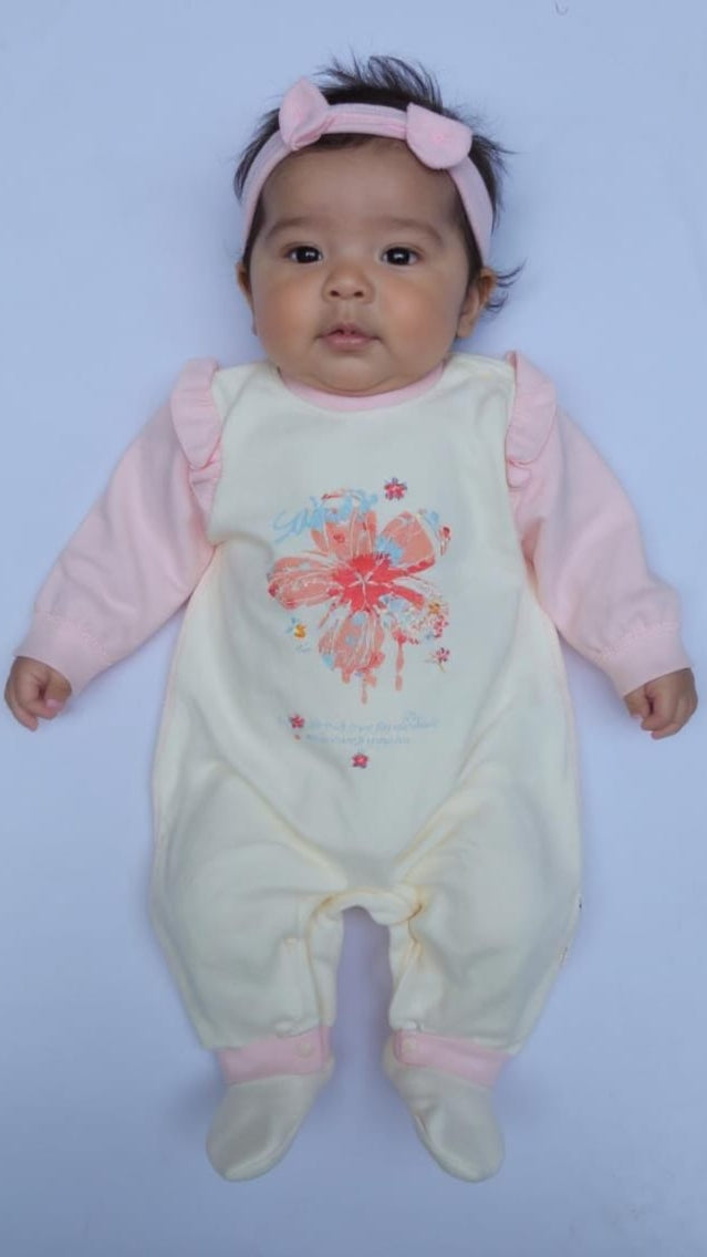 Baby in a light green outfit with pink sleeves and a floral design on a light blue background